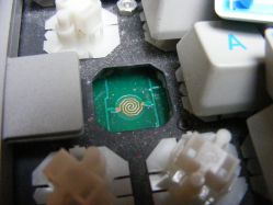 Switch mounting plate with switch removed and PCB visible below